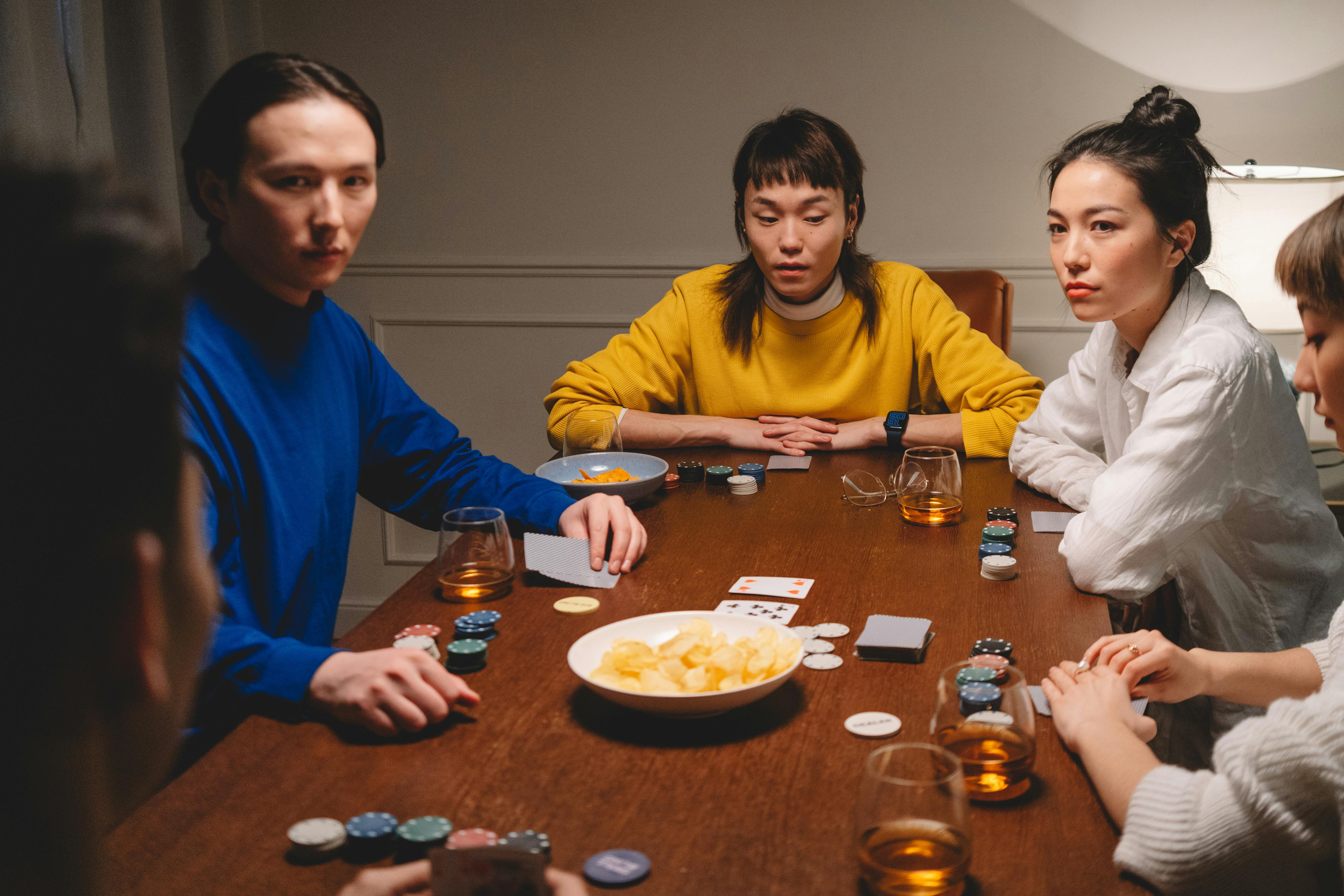 A group of friends playing poker indoors, enjoying leisure time together with snacks and drinks.